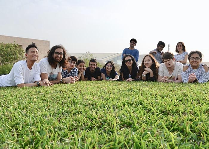 Photo of a group of students laying in the grass and smiling